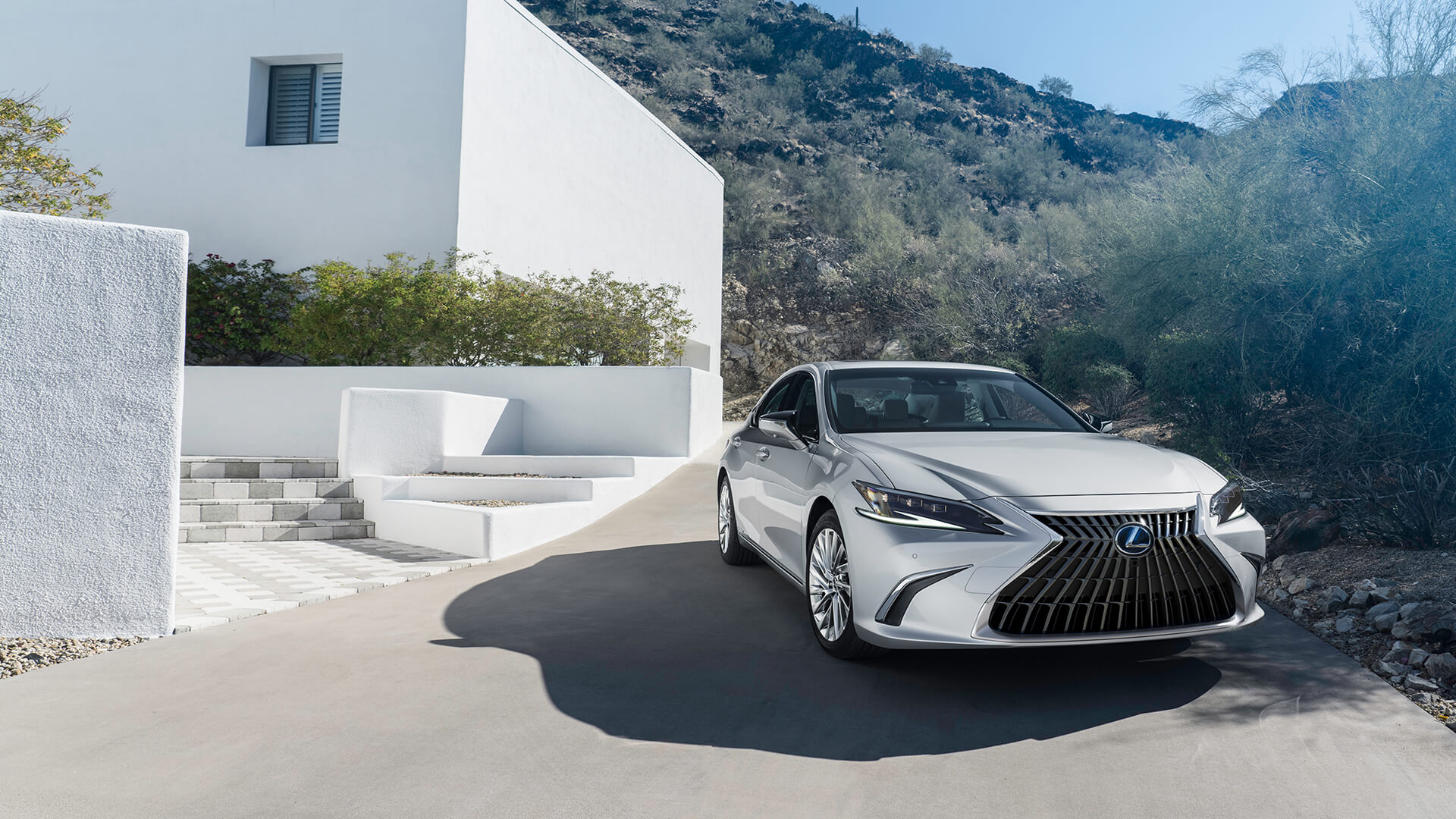 Silver Lexus ES is parked next to a white house.